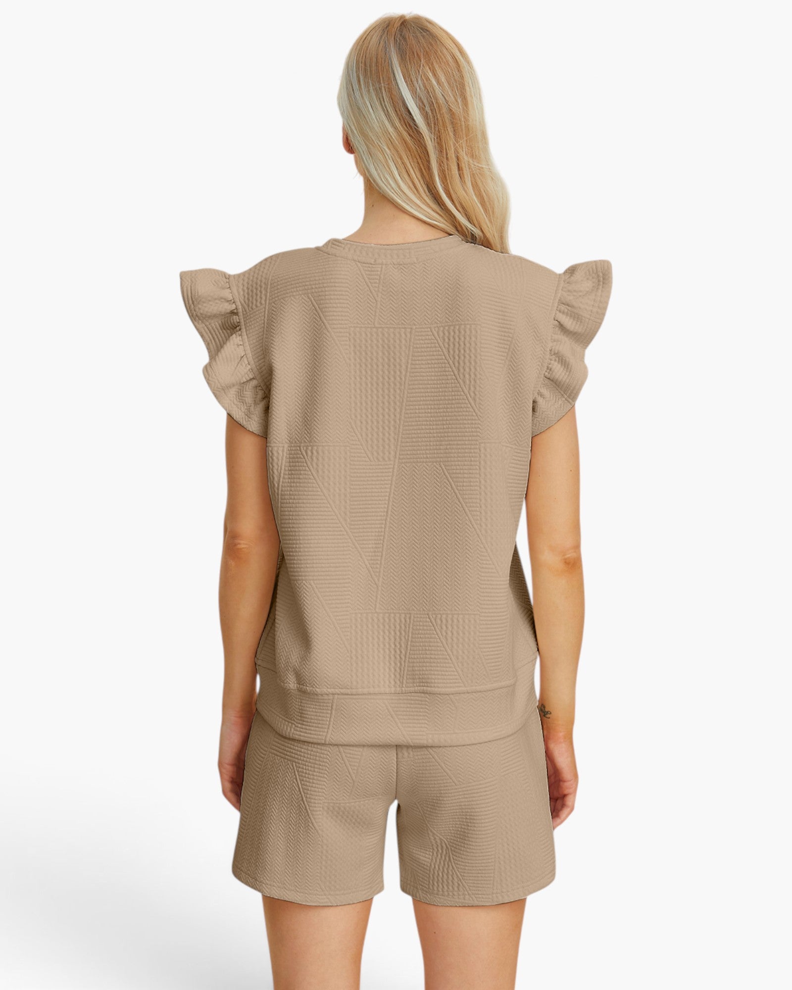 A woman shown from the back wearing a beige short-sleeve top with ruffled shoulders and matching textured shorts against a plain light background.