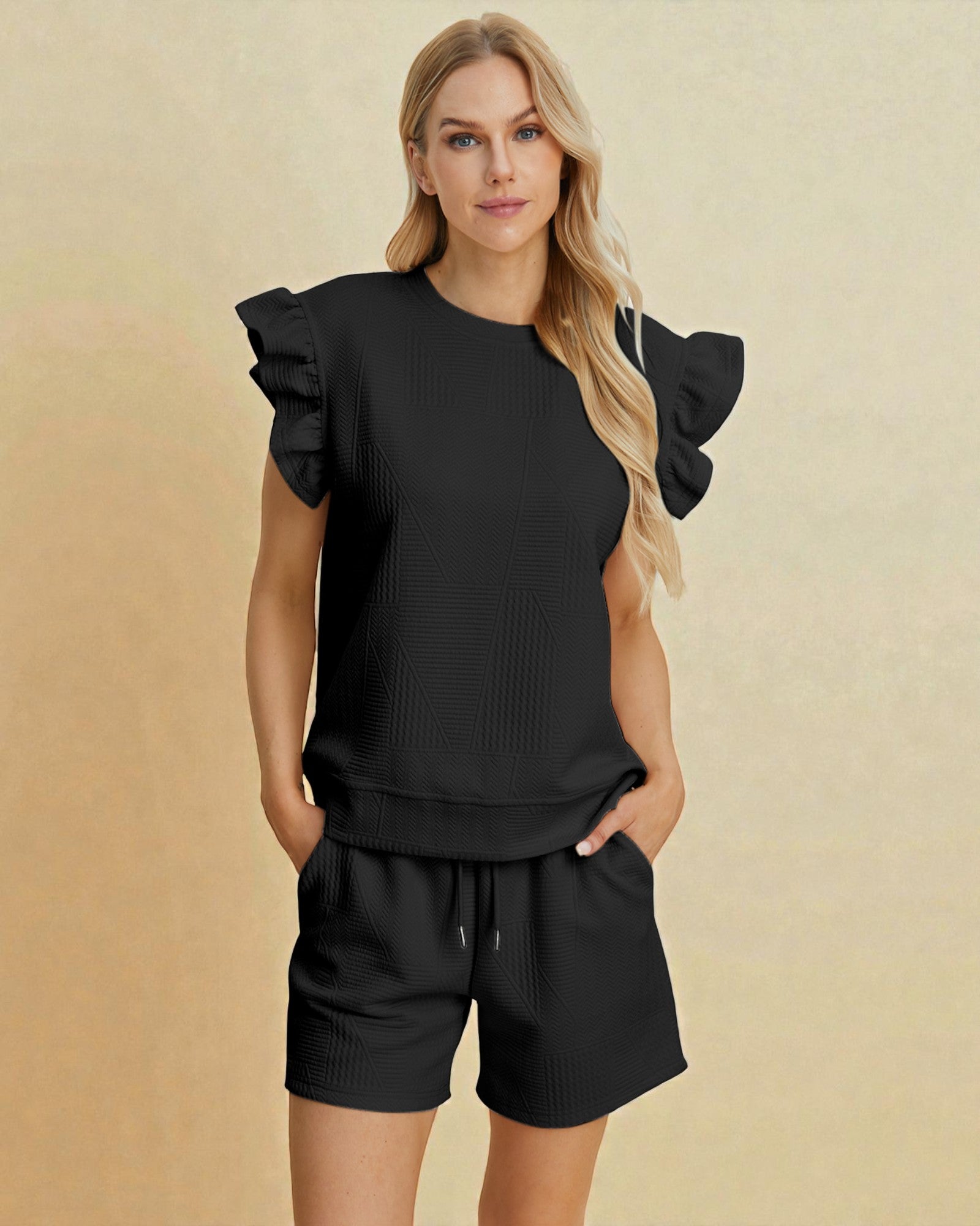 Woman wearing a black outfit with ruffled sleeves on a beige background