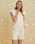 Woman wearing a white outfit with ruffled sleeves against a gold background