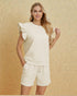 Woman wearing a cream-colored outfit against a beige background