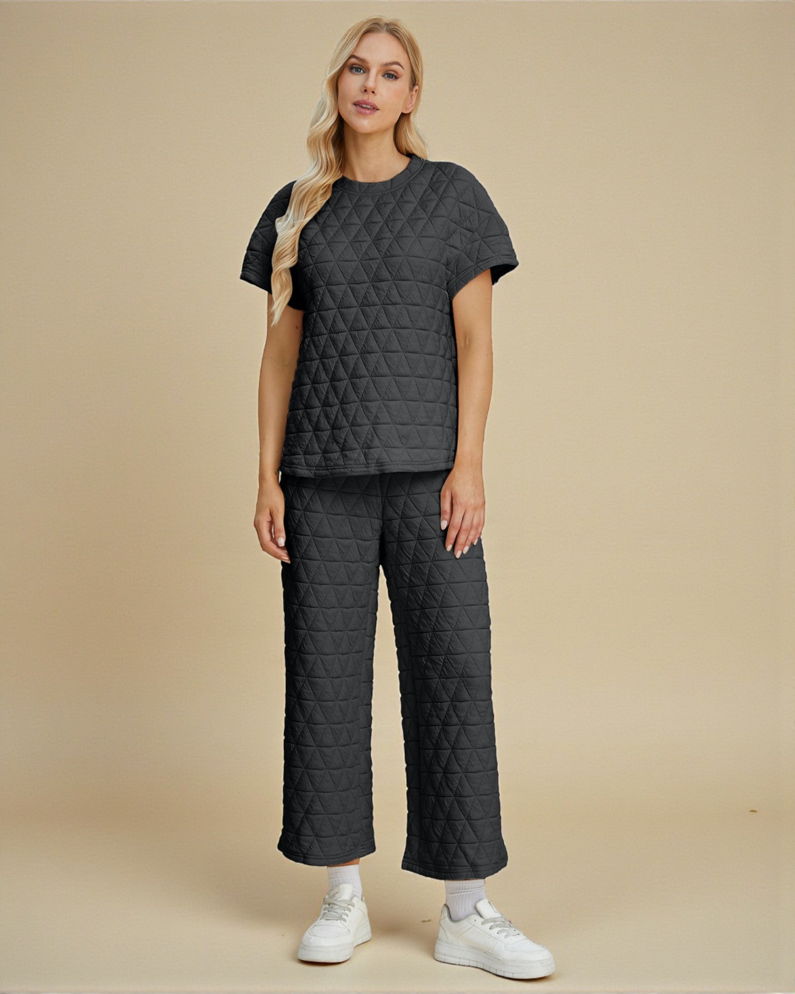 Woman wearing a quilted dark gray outfit on a beige background