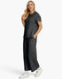 A woman modeling a matching dark gray quilted two-piece set consisting of a short-sleeve top and wide-leg pants, styled with white sneakers against a plain white studio background.
