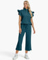 A woman modeling a matching two-piece outfit consisting of a teal ribbed knit top with ruffled cap sleeves and a half-zip neckline, paired with matching wide-leg cropped pants with a drawstring waist, on a light gray studio background.