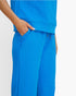 A close-up of a person wearing a bright blue textured matching set, showing the side pocket and hand of the top paired with matching wide-leg pants against a plain white background.