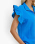 A close-up of a model wearing a bright blue textured top with ruffled cap sleeves and a collar, shown against a plain white background.