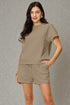 Woman wearing a matching olive green top and shorts set against a gray background