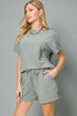 Woman wearing a gray outfit with a matching top and shorts on a gray background