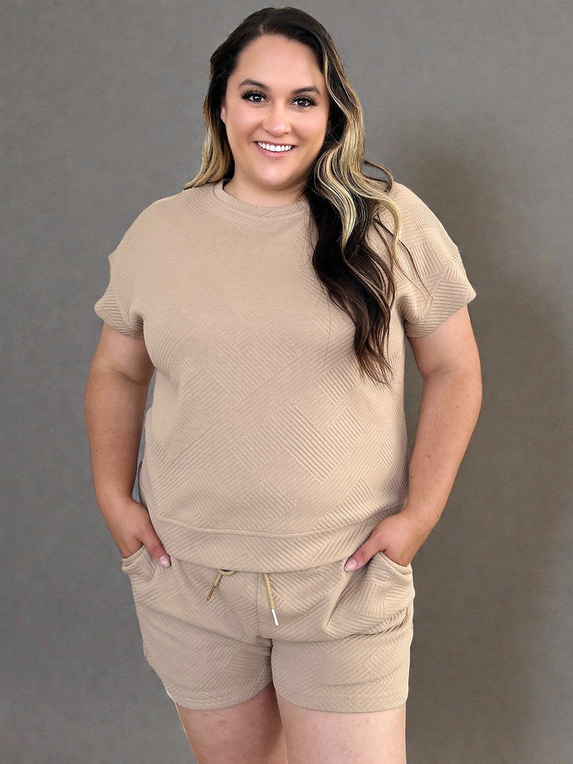 Woman wearing a beige outfit against a gray background