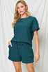 Woman wearing a teal outfit with shorts against a white background