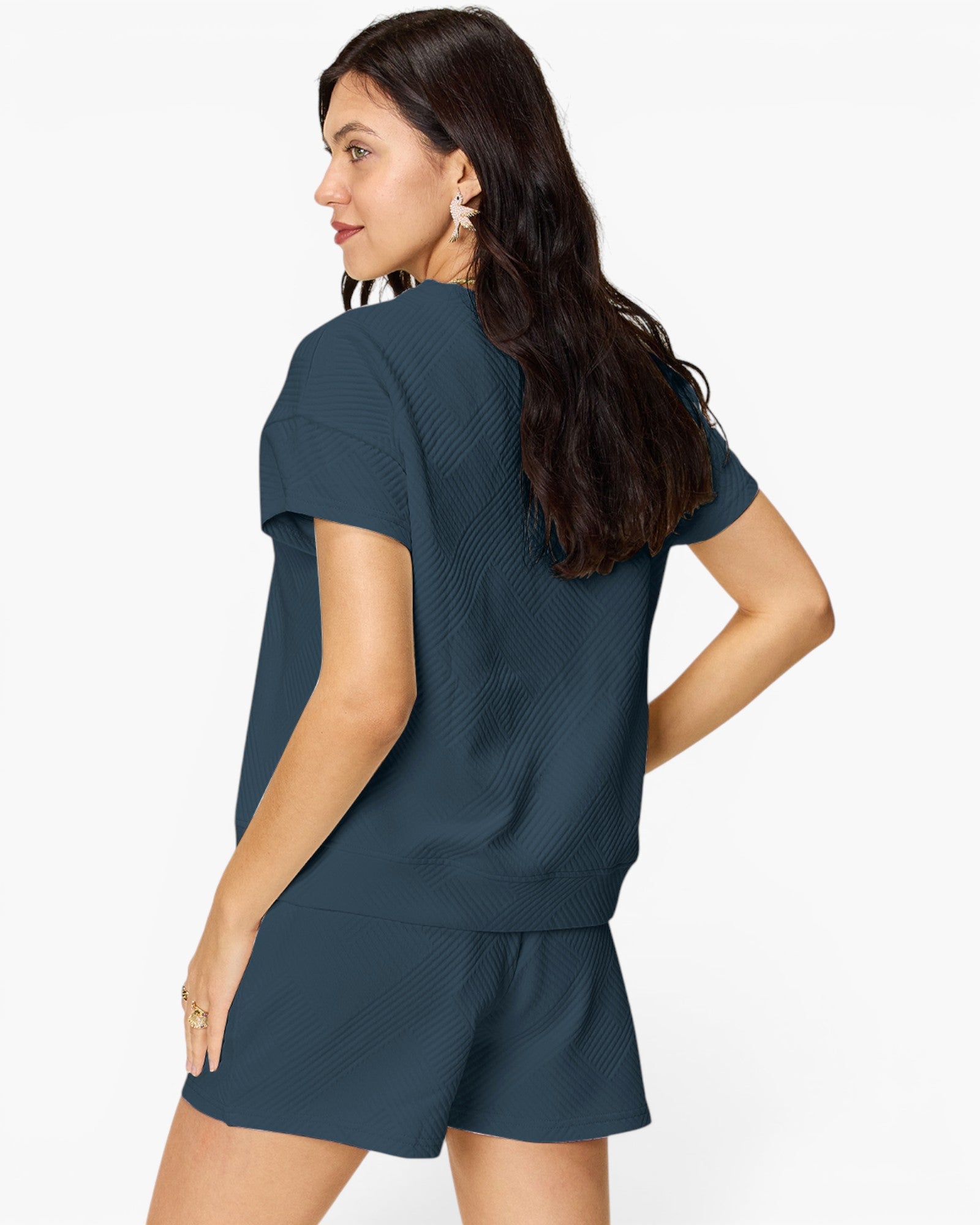 A woman shown from the back wearing a dark slate blue knit short-sleeve top and matching shorts against a plain white background.