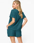 A woman modeling a matching teal short-sleeve top and shorts set, shown from a three-quarter back angle against a clean white studio background.
