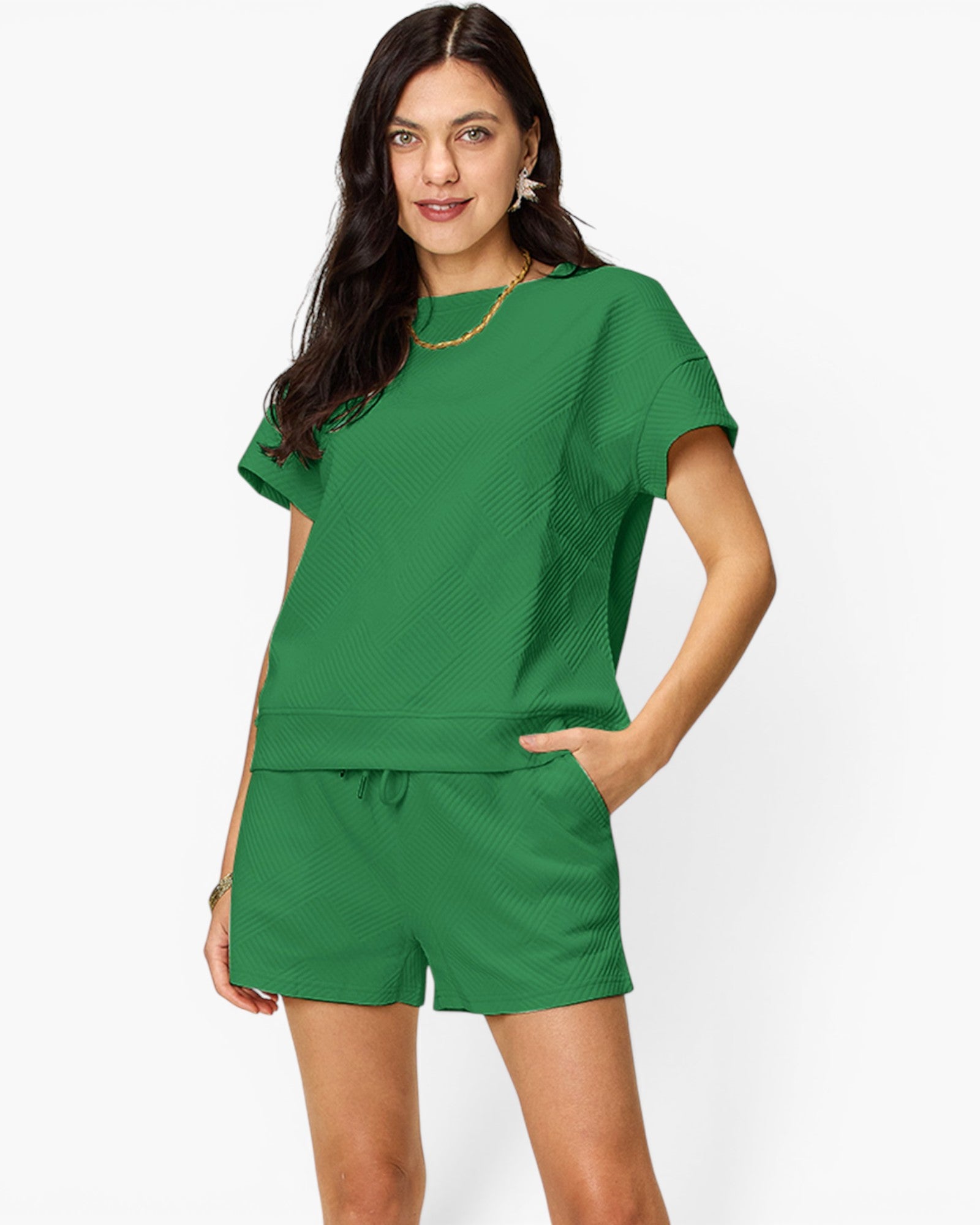 A woman modeling a matching green lounge set consisting of a short-sleeve top and drawstring shorts, photographed against a clean white studio background.