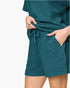 Close-up of a person wearing textured teal drawstring shorts with a matching top, shown against a plain white background.