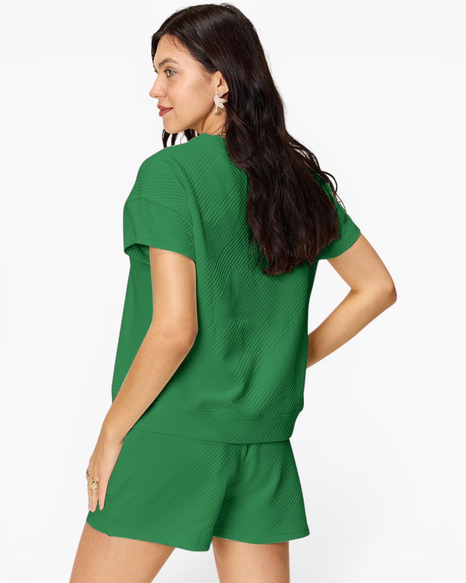 A woman wearing a matching green short-sleeve knit top and shorts set, shown from a three-quarters back view against a plain white studio background.