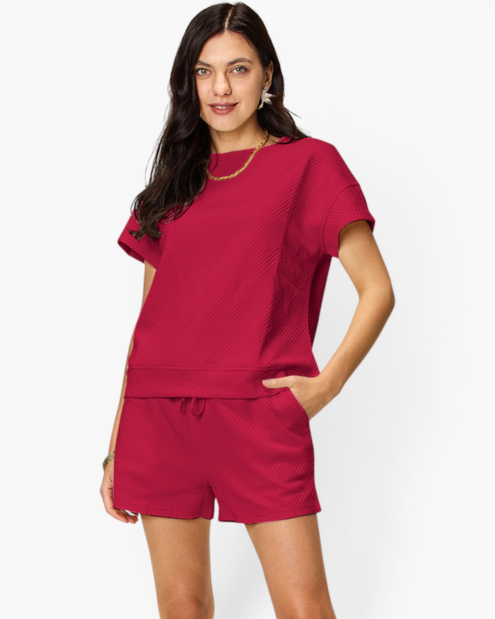 A woman modeling a matching two-piece lounge set in a textured magenta pink fabric, featuring a short-sleeve top and drawstring shorts, against a plain white background.