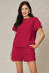 Woman wearing a red outfit with a textured pattern against a neutral background