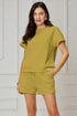 Woman wearing a green outfit against a light gray wall