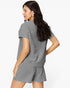 A woman wearing a gray short-sleeve top and matching shorts with a textured waffle pattern, shown from a three-quarters back view against a plain white background.
