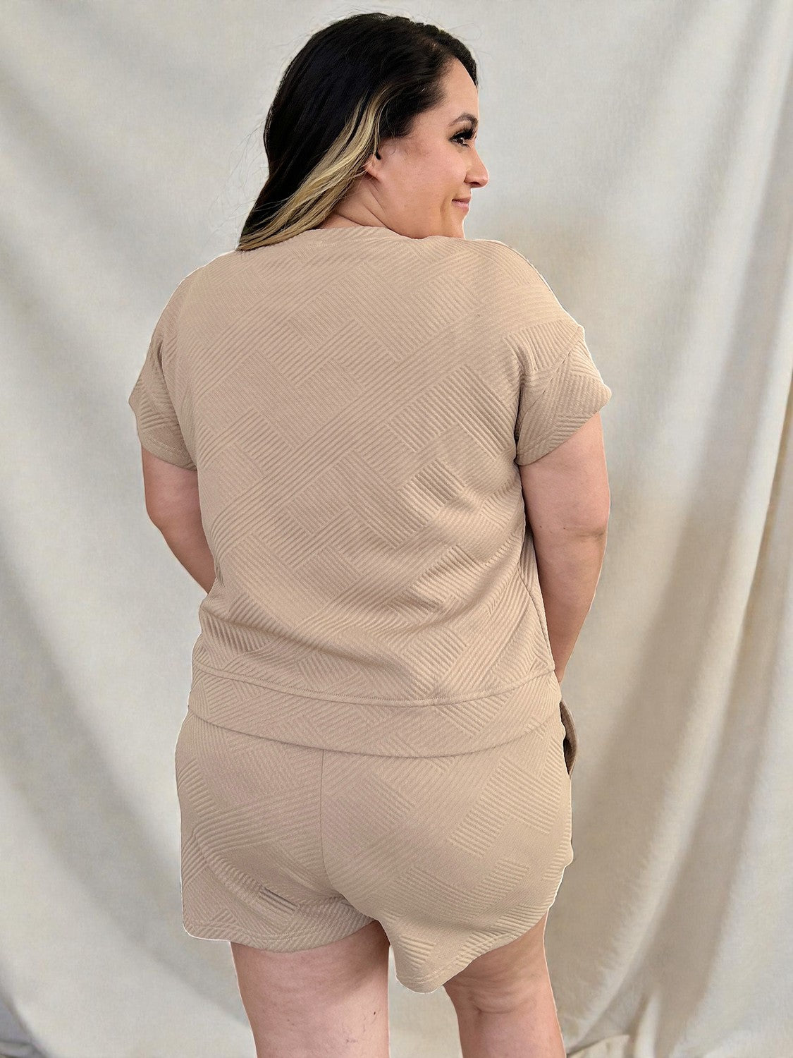 Woman wearing a beige outfit against a plain background