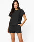 A woman modeling a black short-sleeve crewneck sweatshirt and matching black drawstring shorts against a plain white studio background.