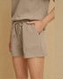 Beige textured shorts worn by a person on a beige background