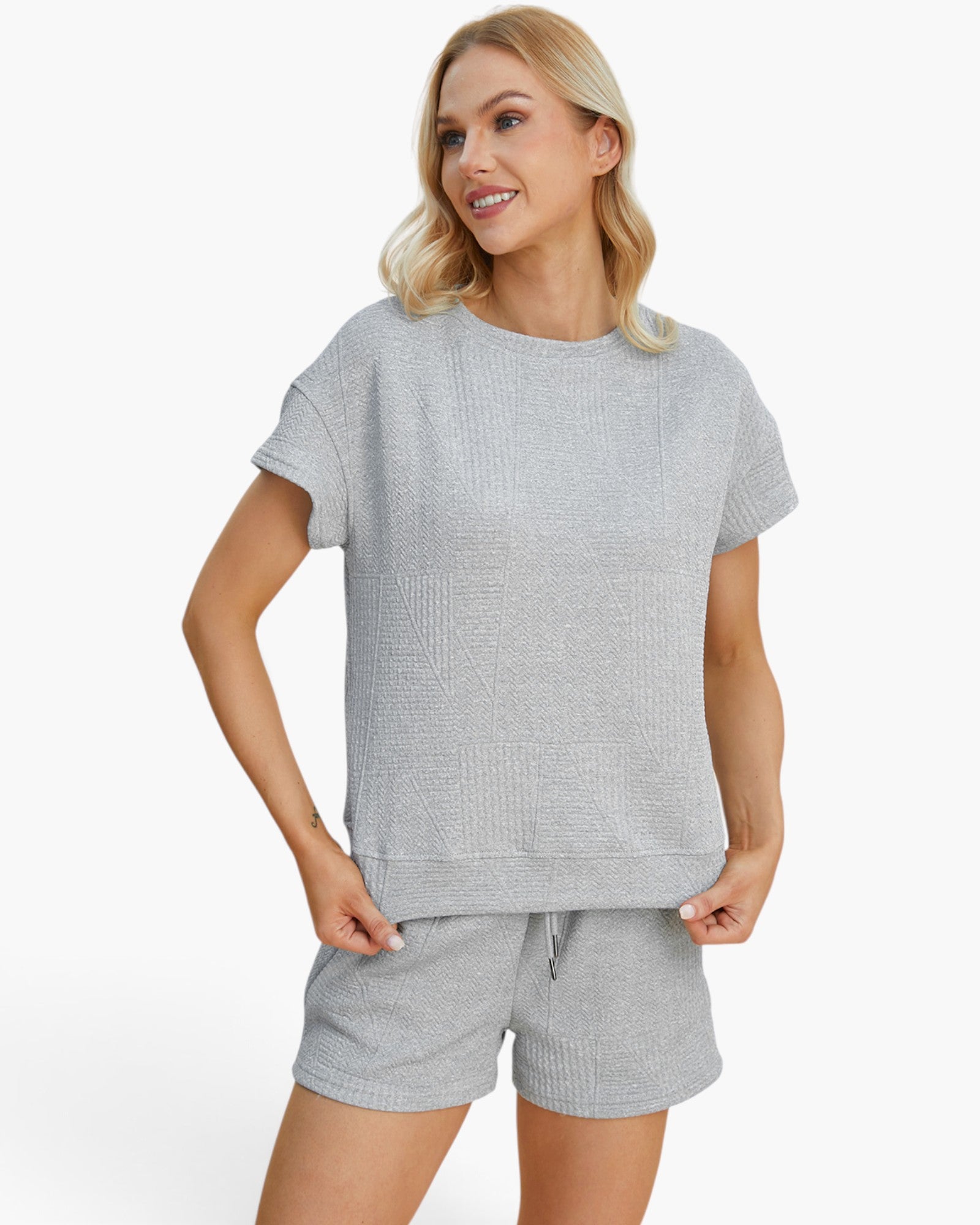 A woman modeling a light gray textured short-sleeve top and matching shorts against a clean white background.