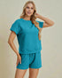 Woman wearing a teal outfit with a matching top and shorts on a beige background
