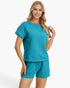 A woman modeling a matching two-piece lounge set in a bright turquoise color, featuring a short-sleeve waffle-knit top and coordinating shorts, against a clean white background.