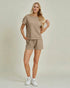 Woman wearing a beige outfit with shorts and a top on a plain background