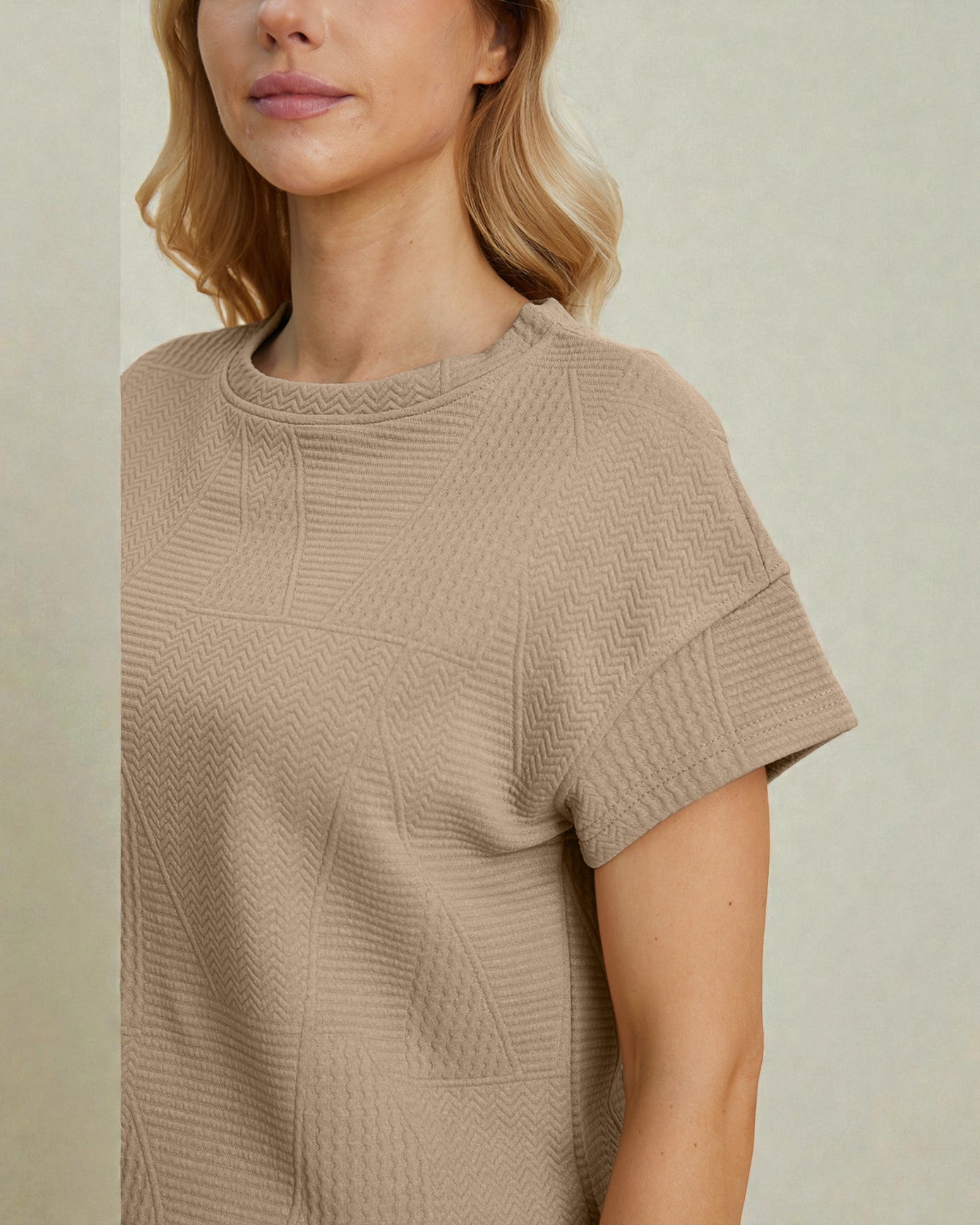 Woman wearing a beige textured sweater against a neutral background