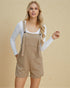 Woman wearing beige overalls against a beige background
