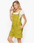 A woman modeling a bright yellow-green overall romper with a textured waffle pattern, worn over a white short-sleeve t-shirt, against a plain white background.