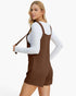 A woman modeling a brown ribbed overall romper over a white long-sleeve top, shown from a three-quarter back angle against a plain white studio background.