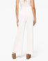 A model shown from the back wearing high-waisted, wide-leg white pants with a matching white top and brown block-heel sandals, set against a plain white studio background.