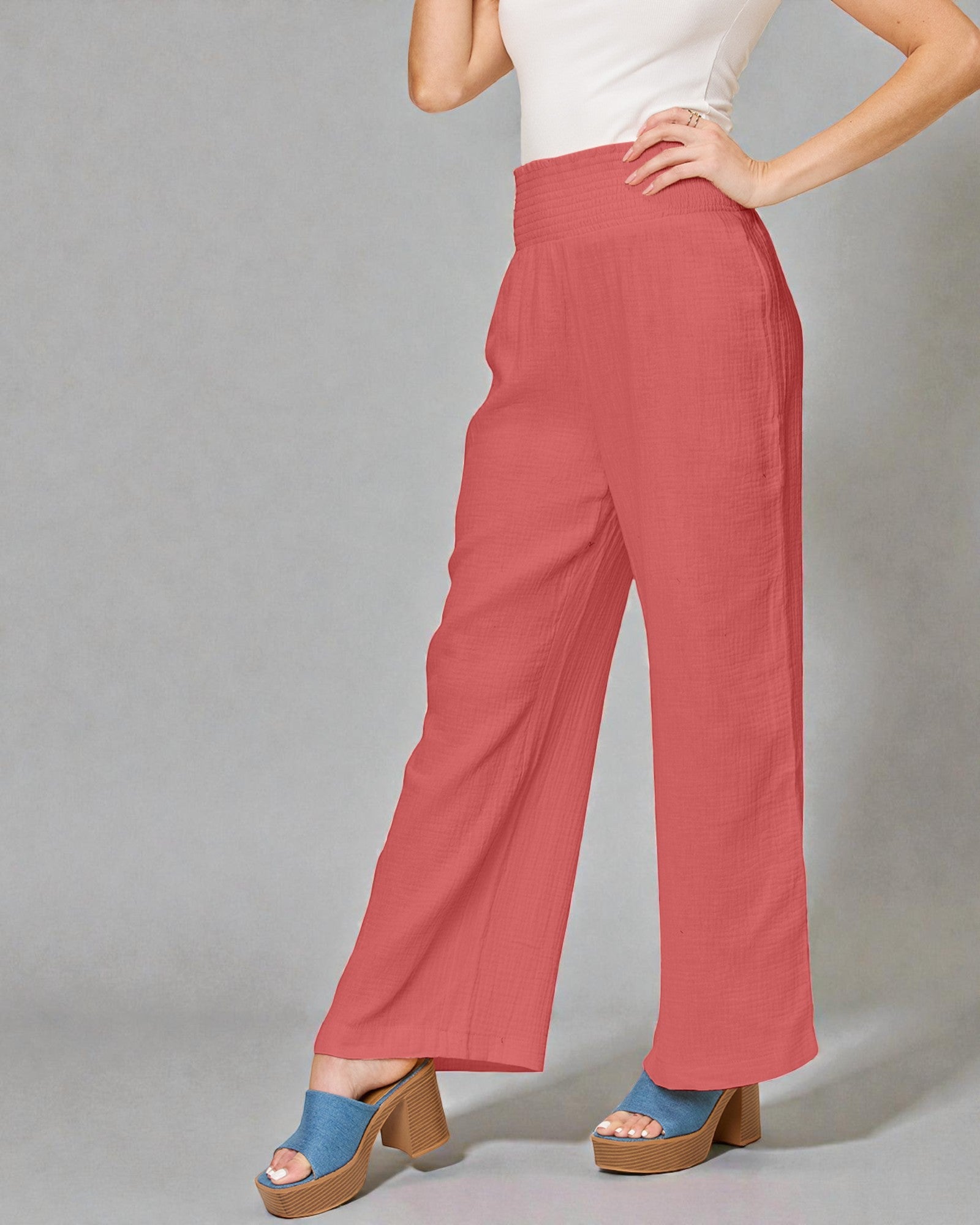 Person wearing coral pants with a plain background
