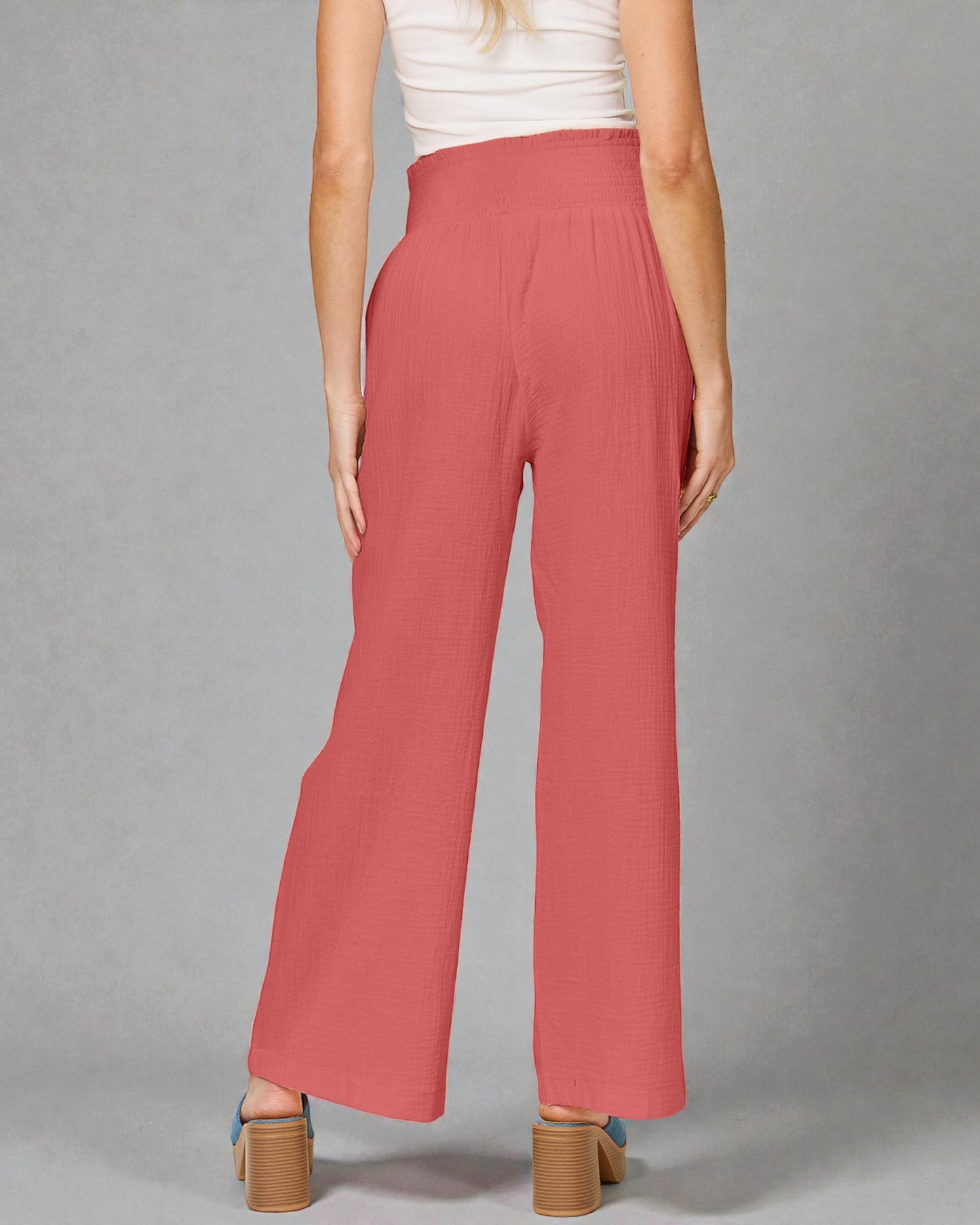 Person wearing pink wide-leg pants on a gray background