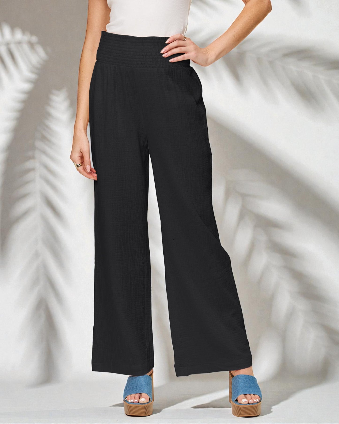 Person wearing black wide-leg pants with a white background