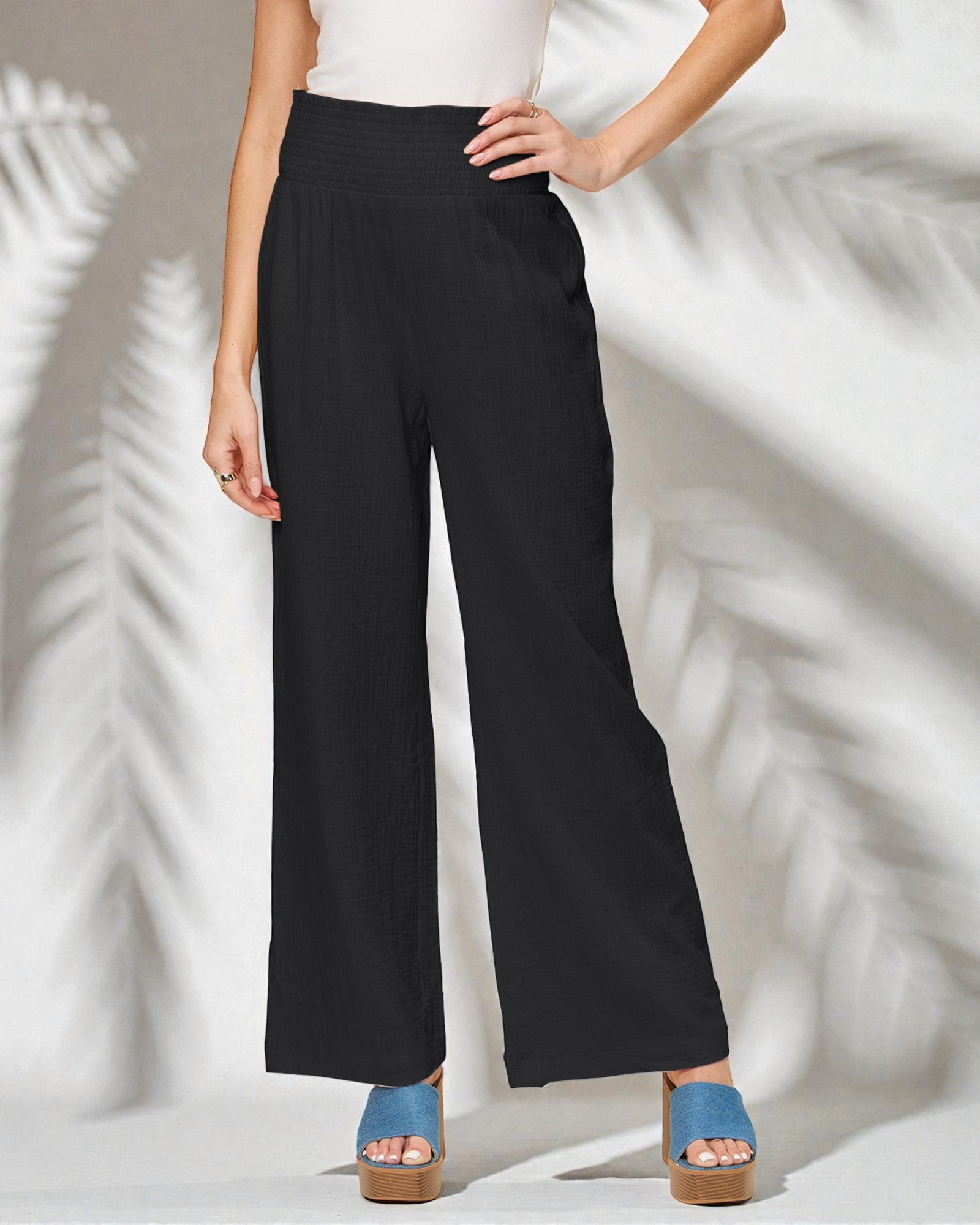 Person wearing black wide-leg pants with a white background