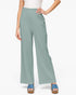 A model wearing high-waisted, wide-leg pants in a dusty sage green color, paired with a white top and blue platform sandals, against a plain white background.