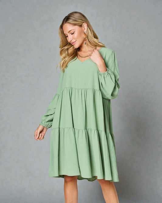 Woman wearing a green dress against a gray background