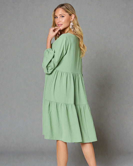 Woman wearing a green dress against a gray background