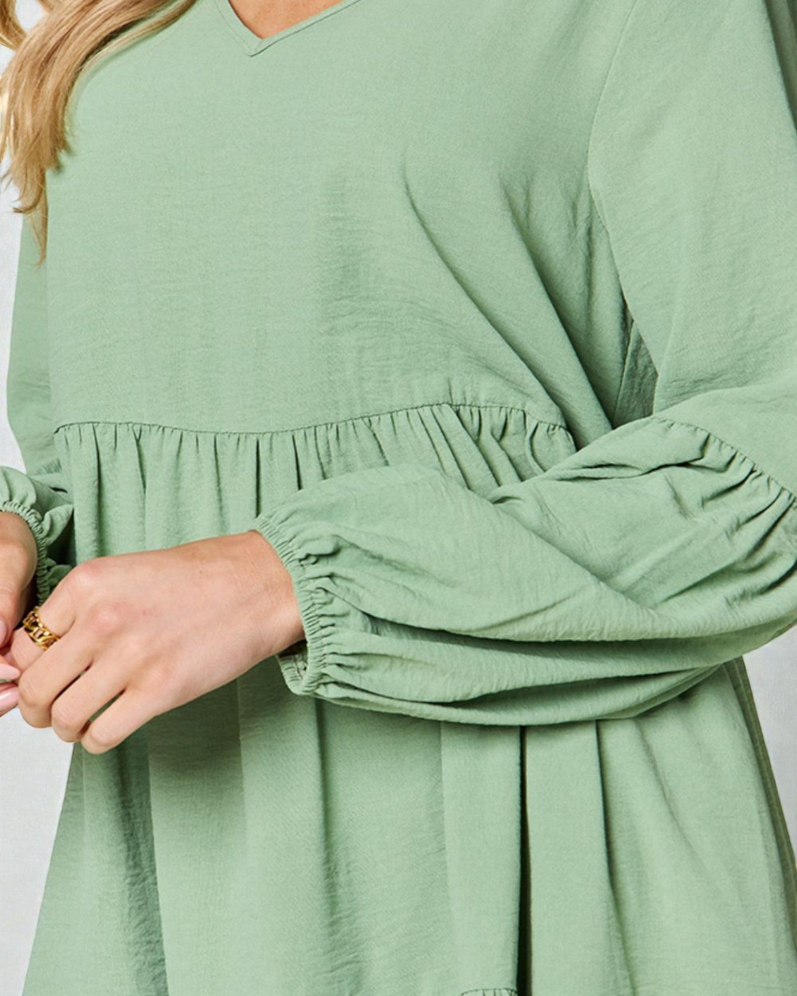 Green dress with long sleeves and a V-neckline on a plain background