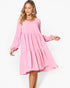 A woman modeling a pink tiered long-sleeve dress with a V-neckline against a plain white studio background.