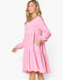 A woman modeling a pink tiered long-sleeve dress with a V-neckline and elbow-length sleeves, posed against a clean white studio background.