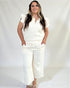 Woman wearing a white outfit with ruffled sleeves against a plain background