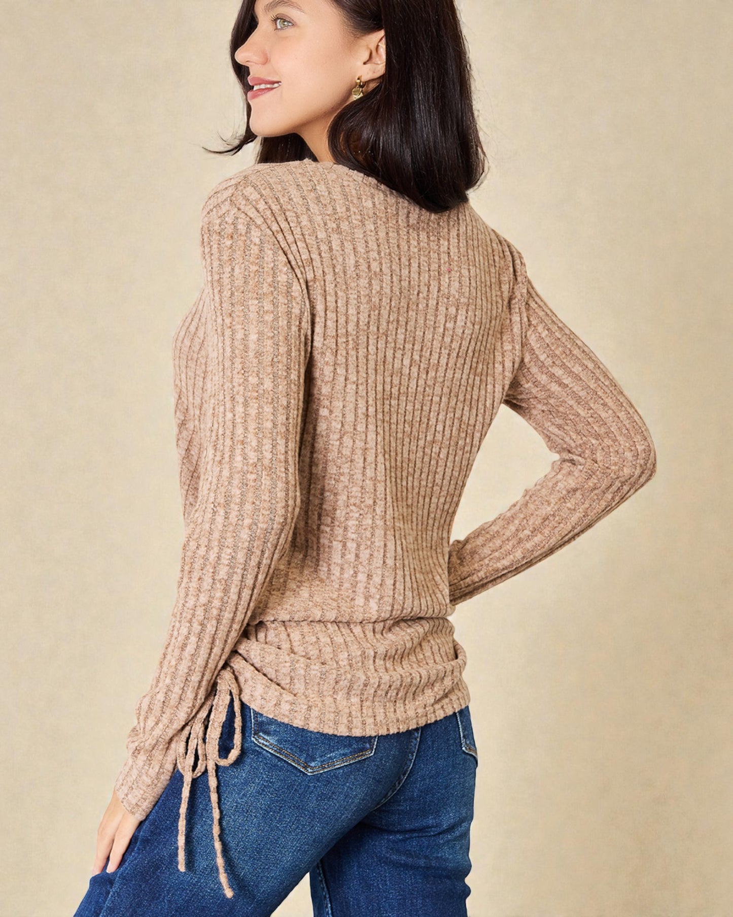 Woman wearing a beige sweater with a neutral background