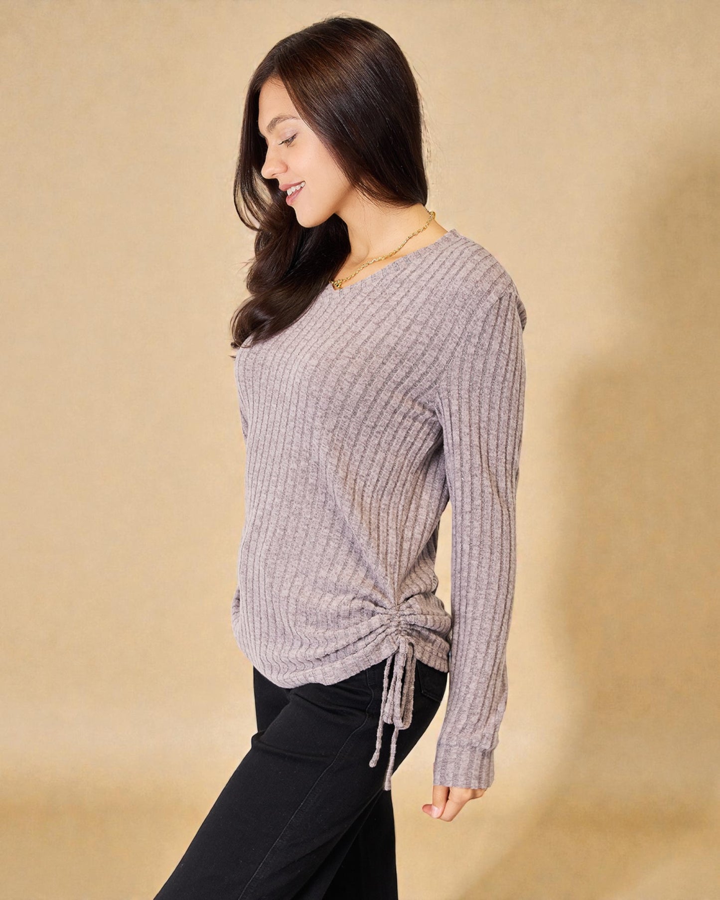 Woman wearing a gray sweater with a beige background