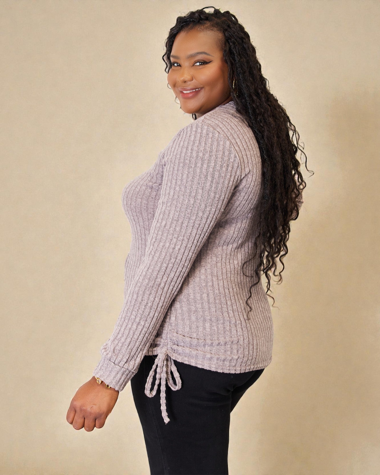 Woman wearing a light purple sweater with a beige background