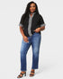 Woman wearing a black top with silver trim and blue jeans on a white background