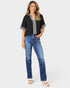 Woman wearing a black top with lace trim and blue jeans on a white background